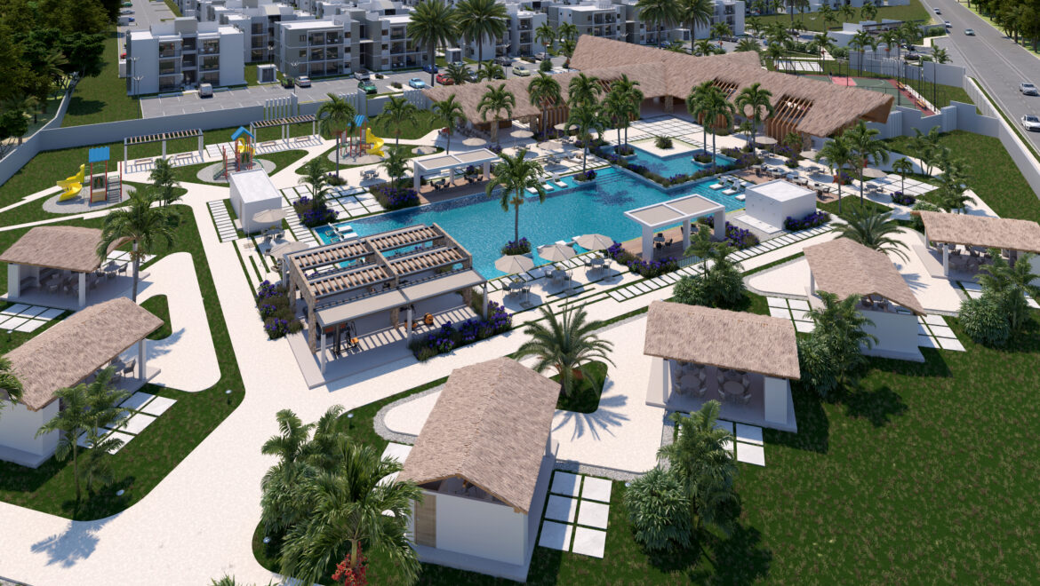 Aerial view of a resort-style pool complex with palm trees, thatched-roof pavilions, lounge areas, and surrounding white buildings.