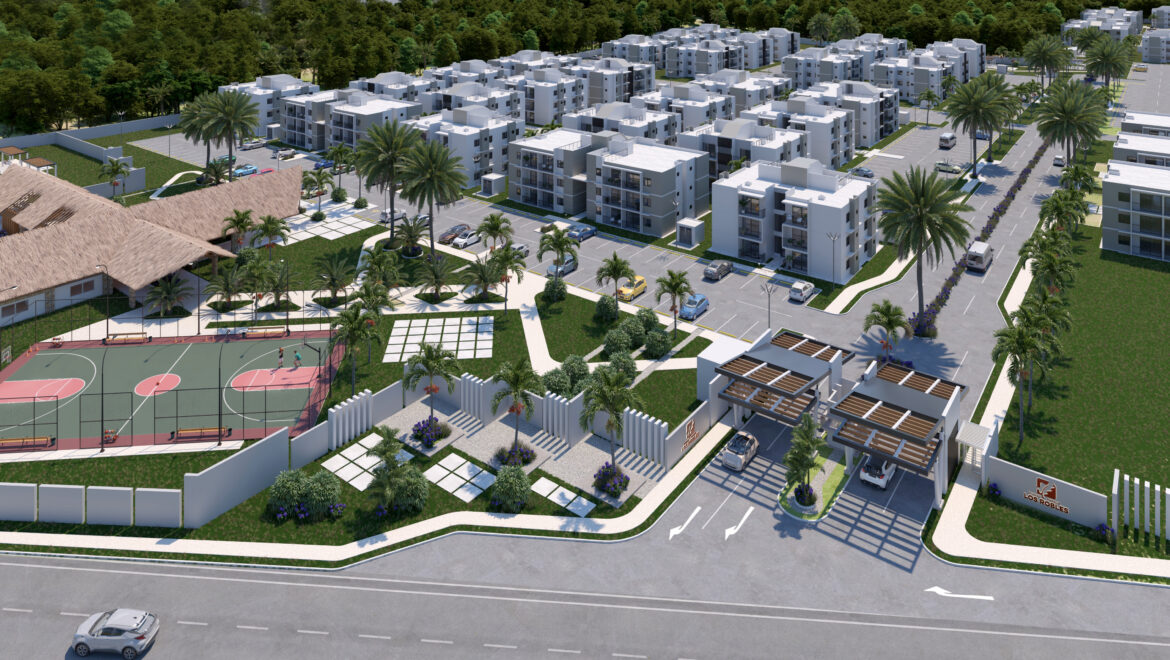 Aerial view of a modern gated residential complex with white apartment buildings, palm trees, and a basketball court surrounded by greenery and roads.
