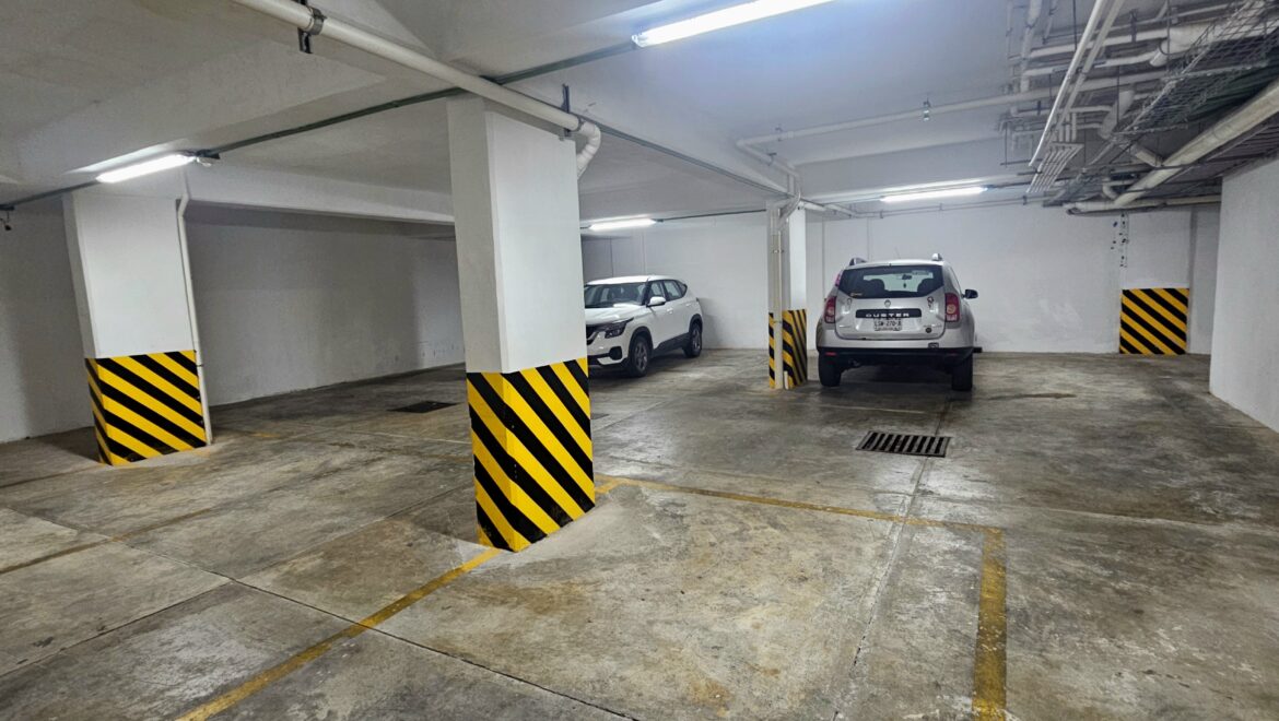Underground parking garage with striped yellow-and-black columns and two parked SUVs in the center area.