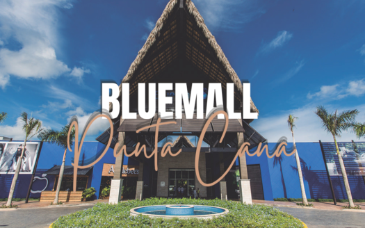 Exterior of Blue Mall Punta Cana with a blue building facade, palm trees, and a circular fountain in front; large white 'BLUE MALL Punta Cana' text overlay.