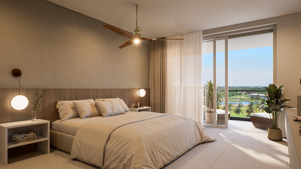 Hotel bedroom with a king bed, soft beige bedding, and two side tables leading to a balcony with a tropical view.
