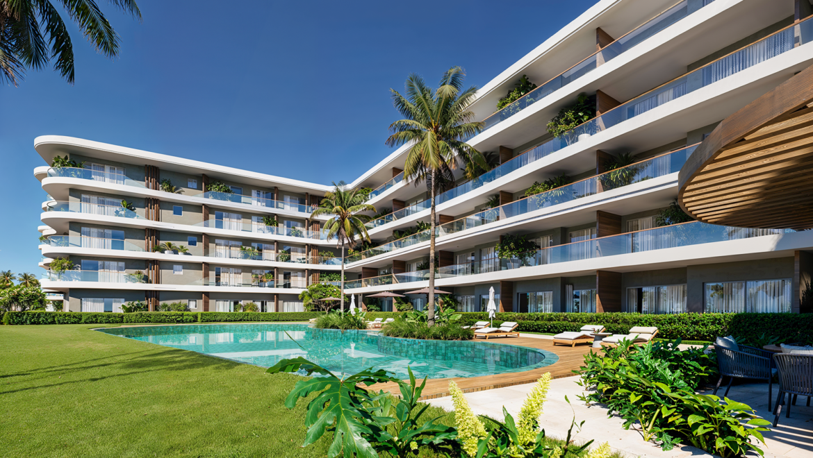 Resort building with curved balconies, glass railings, and palm trees around a pool under a blue sky