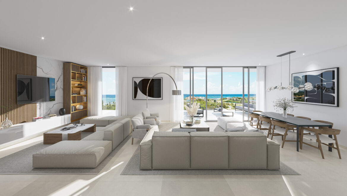Spacious contemporary living room with grey sectional sofas, wood shelving, and floor-to-ceiling windows showing an ocean view.