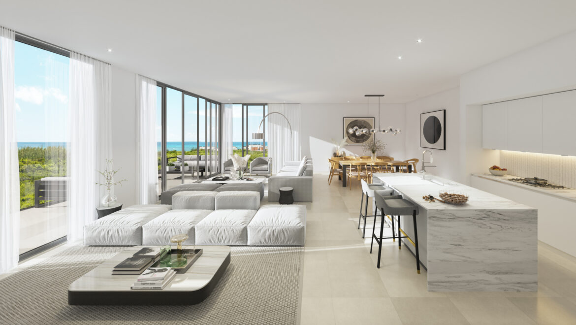 Bright, open-concept living space with floor-to-ceiling windows looking out to the ocean and white/gray furniture.