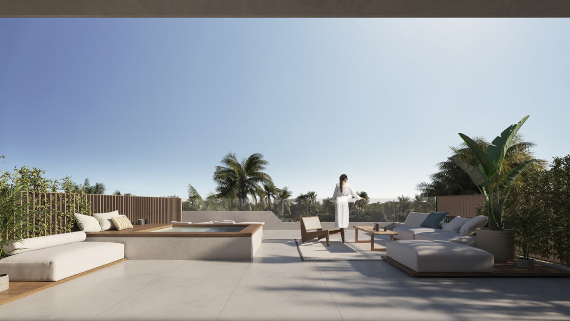 Outdoor rooftop lounge with white cushioned seating, wooden accents, and palm trees under a clear blue sky; a person in a white robe stands at center.