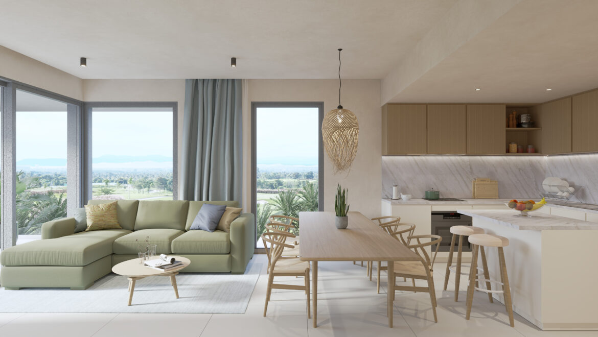 Open-concept living room and kitchen with a pale green sectional sofa, wooden dining table, and large windows showing greenery outside; bright, modern space.