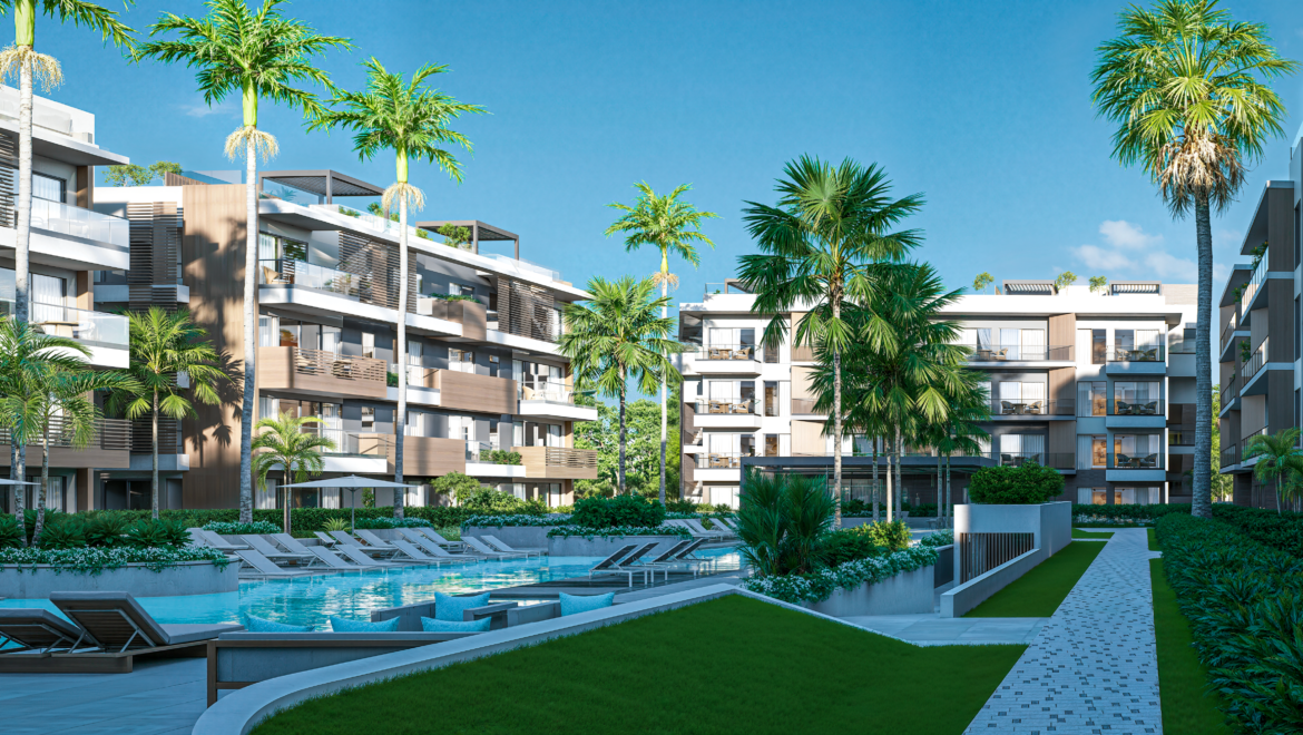 Modern resort-style apartment complex surrounding a swimming pool with lounge chairs and palm trees under a bright blue sky.