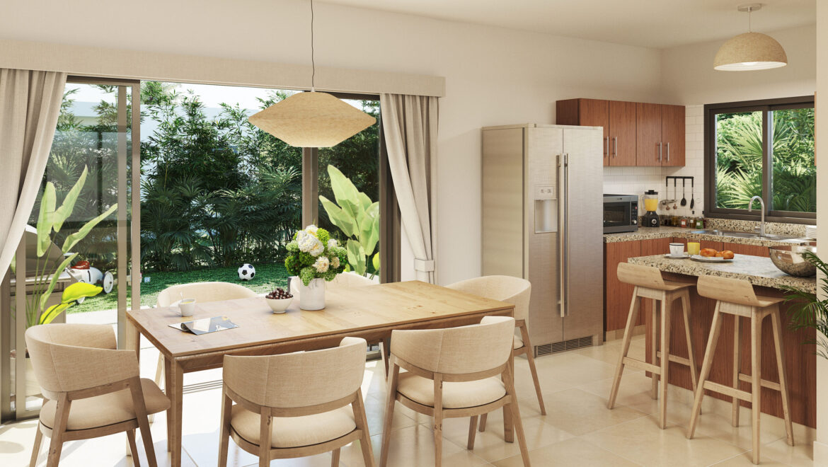 Bright kitchen and dining area with a wooden table, beige chairs, and an island; large windows show lush outdoor greenery and a sunny garden.