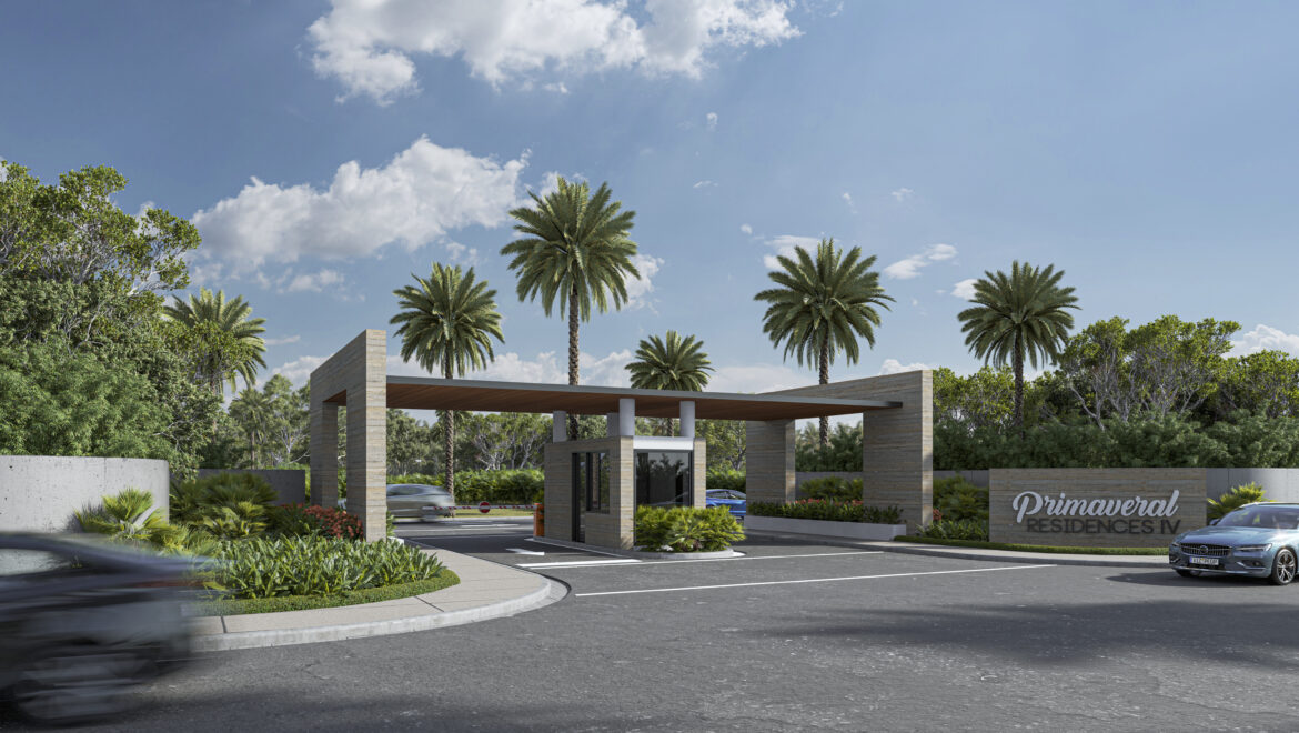 Gated entrance to Primavera Residences IV with stone pillars, landscaping, and tall palm trees under a blue sky.