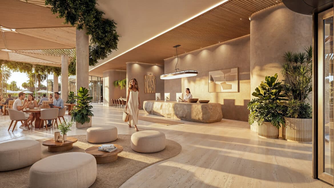 Spacious hotel lobby with a curved stone reception desk, guests at round tables, and lush indoor plants.