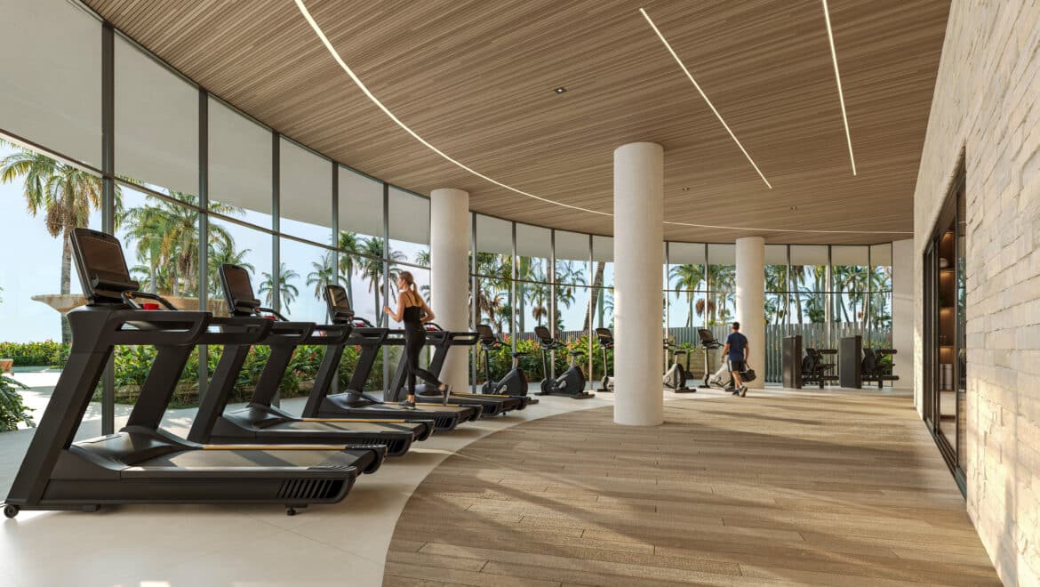 Row of treadmills in a modern glass-walled gym, with palm trees visible outside and a woman running on one treadmill.