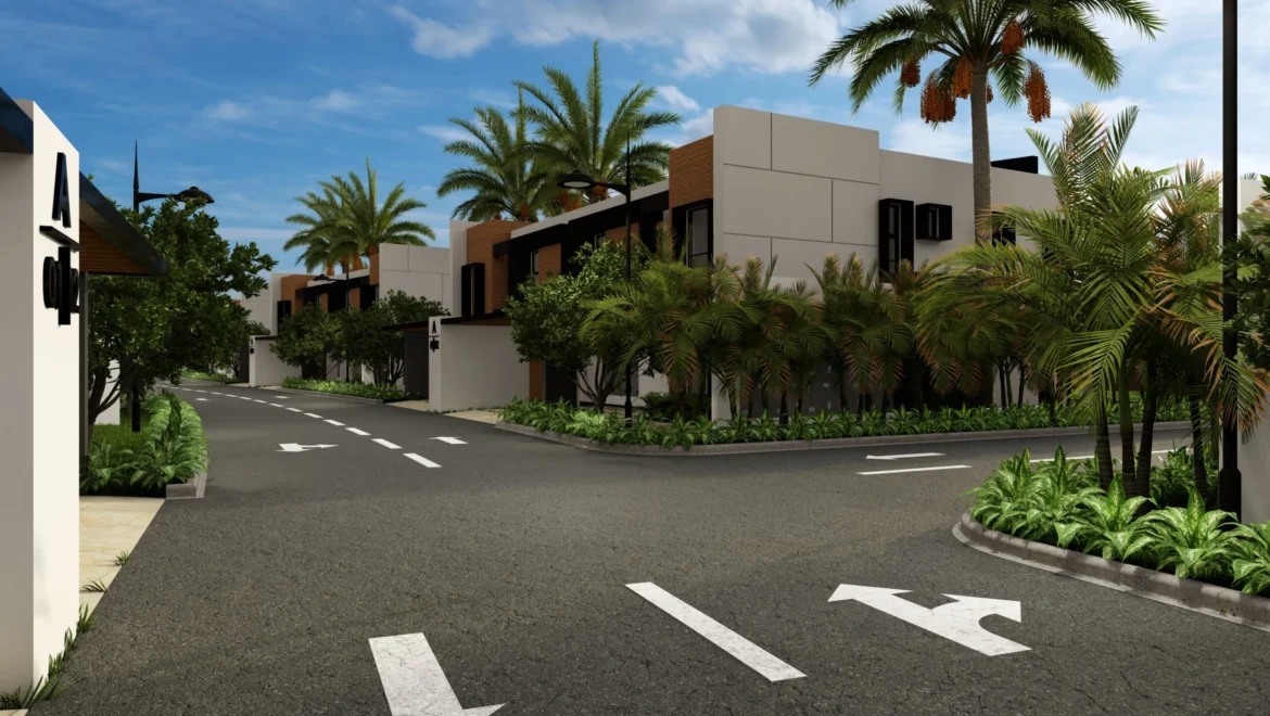 Modern townhouse street with palm trees and lush tropical landscaping along a curved road under a blue sky.