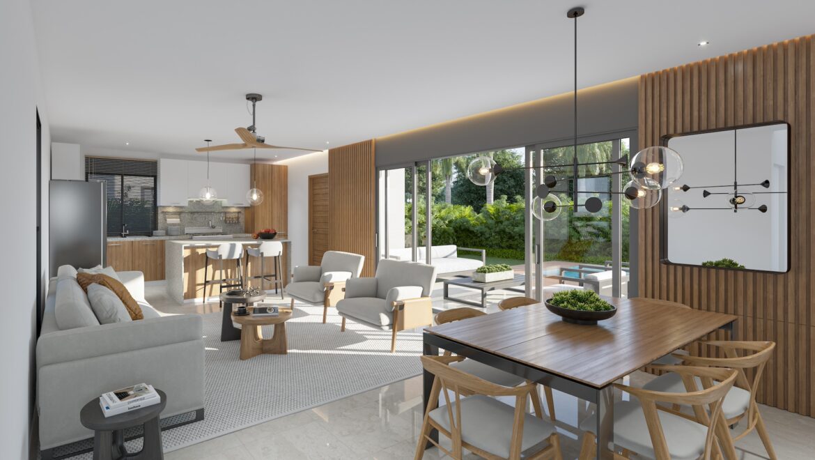 Open-plan living room with a wood-accent wall, dining table, and kitchen island overlooking a garden through large glass doors.